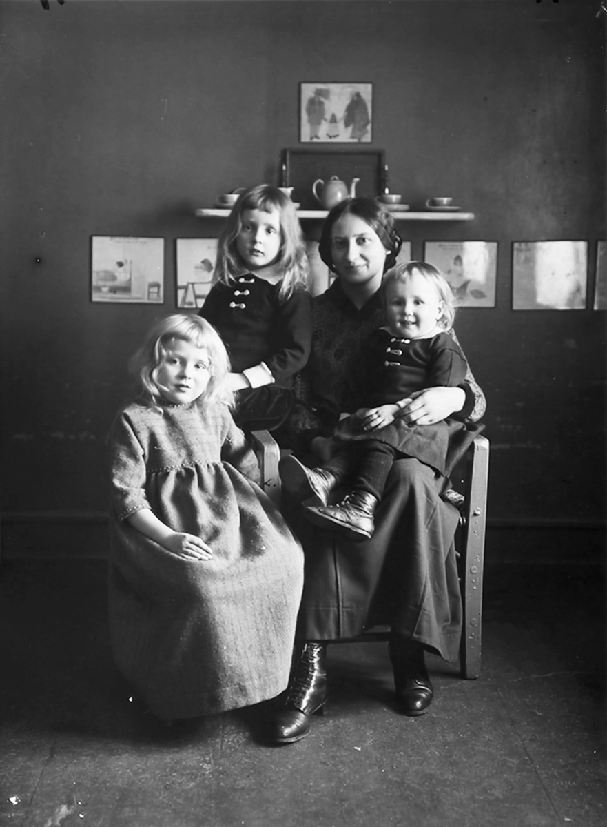 Gruppebilde. Familie. 4 personer. Ei voksen kvinne og 3 jenter. Bildet er tatt i Lofoten.