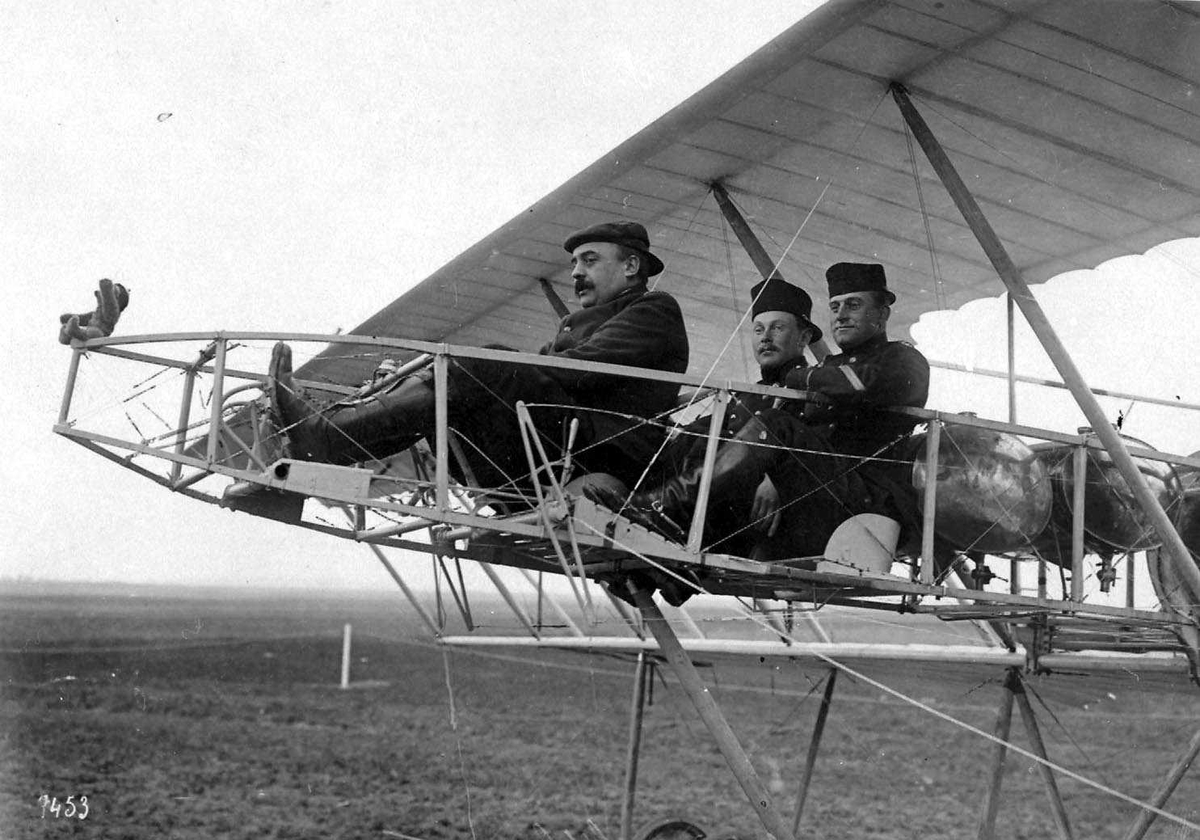 Ett fly på bakken, Henry Farman. Tre personer, menn i flyet.