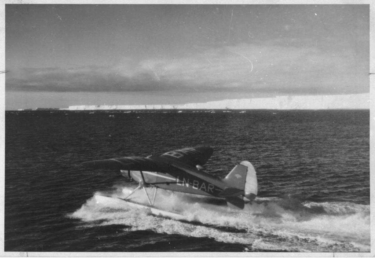 Ett fly i fart på havet Stinson SR.8 EM, LN-BAR. Iskanten i bakgrunnen.