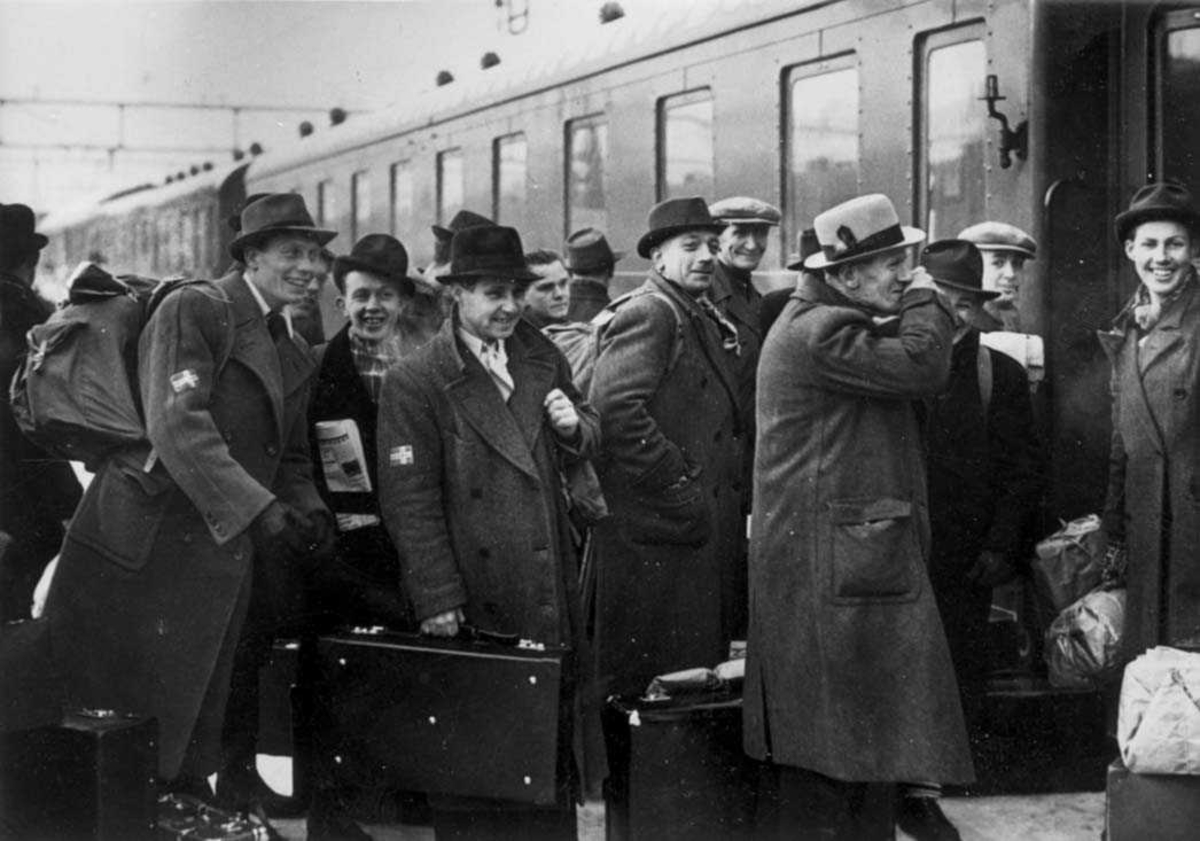 En gruppe personer som er klar til avreise foran et tog.
