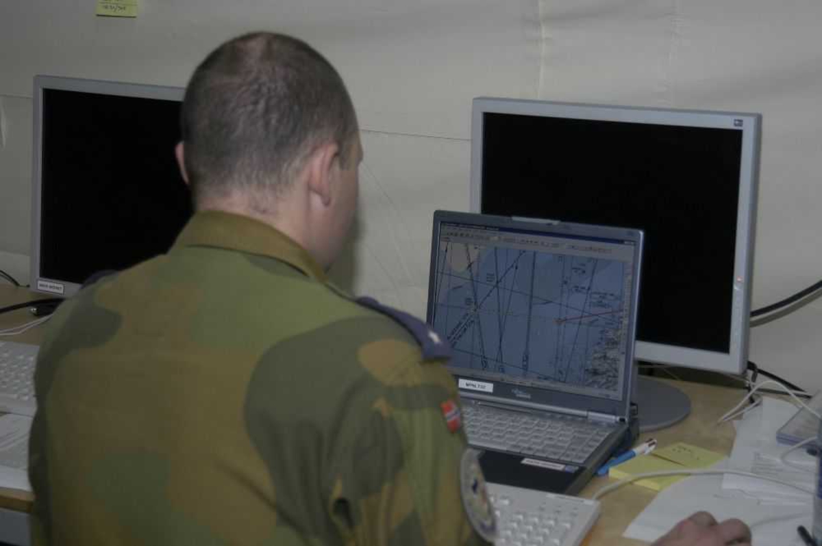 En personer, mann i militæruniform. Kontor inne i et telt med PC-utstyr..