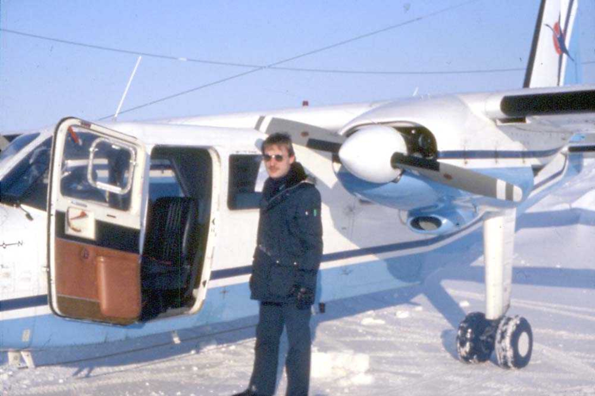 Lufthavn. Ett fly på bakken, Britten-Norman BN-2A-21 Islander, LN-MAG fra Norving. En person står foran flyet. Snø på bakken.