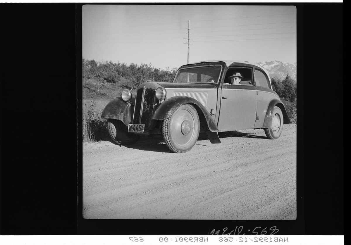 Kvinne med hatt sitter i en bil. førkrigs DKW W4454. Grusvei.