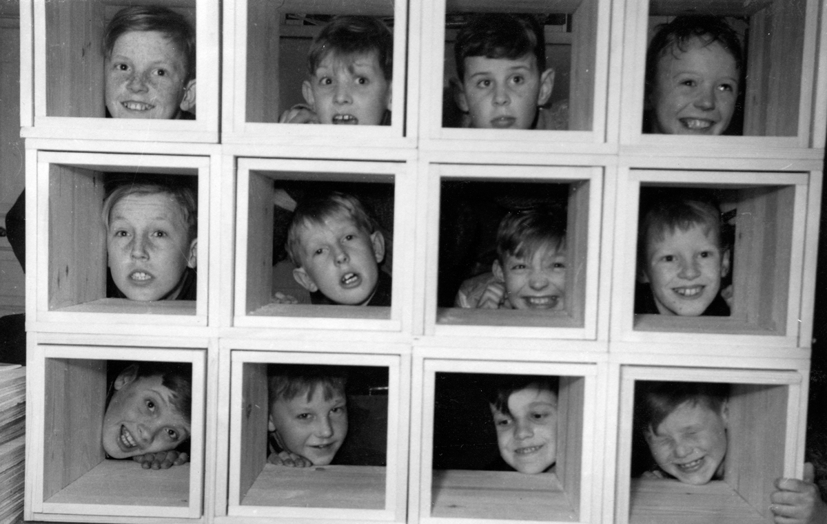 Pojkar tittar fram genom uppbyggda lådor på Vinterstugan i Jönköping. Det var bolaget som ägde huset och det fanns två tanter som höll vakt.