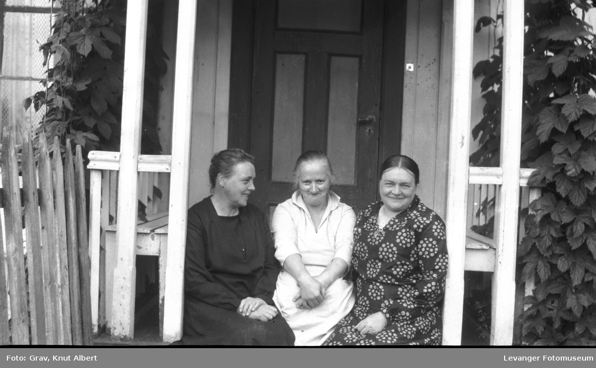 Gruppebilde, tre kvinner  sitter på veranda.