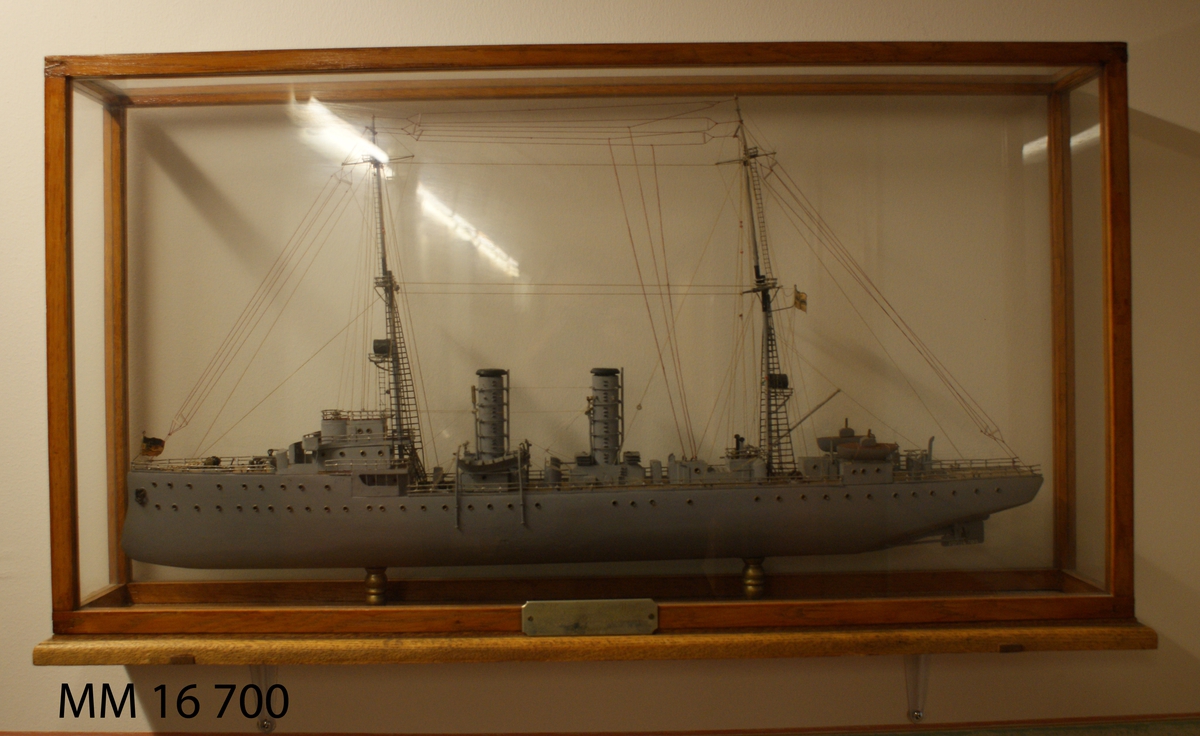 Gråmålad modell av tyska örlogsfartyget Albatross, monterad på ekplatta, samt därutöver glasmonter. På montern nysilverplatta graverad: "Till vännen Ivar Uggla av sina albatrossvänner Julen 1918".
