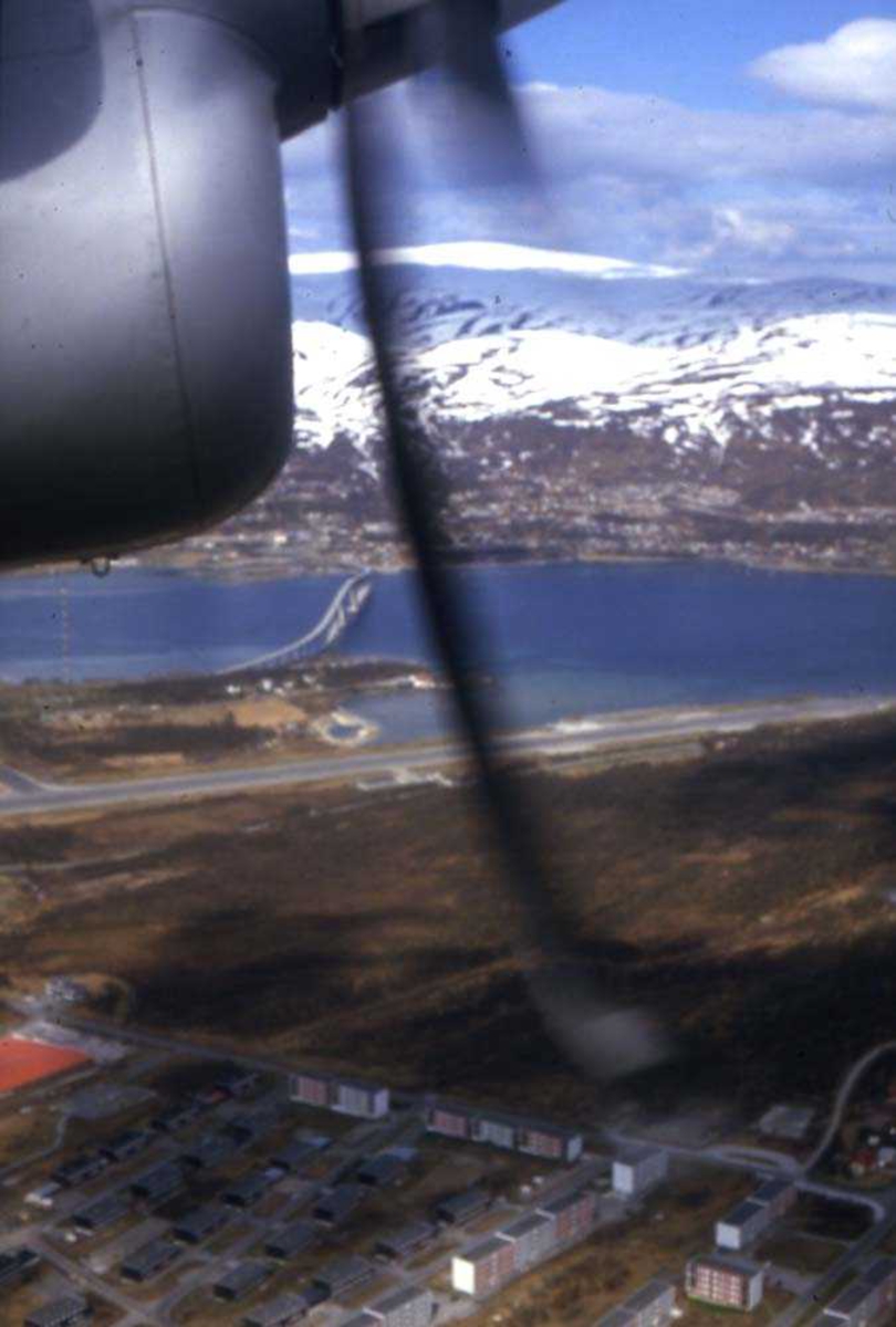 Luftfoto. Fra kabinen i et fly, DHC-7-102 Dash7 fra Widerøe. Tromsø lufthavn, Langnes midt på bildet, og Kvaløysundbroen over Sandnessundet.