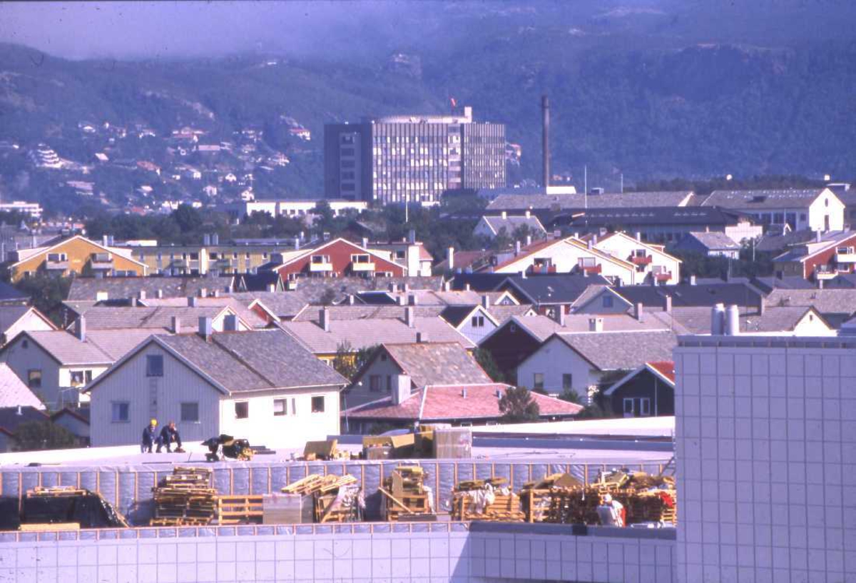 Lufthavn - flyplass. Fotografi fra toppen av flyterminalbygget med Nordland Sentral Sykehus ruvende midt i Bodø. I bakgrunn deler av Rønvikfjellet med Ravnflåget til venstre på bildet.