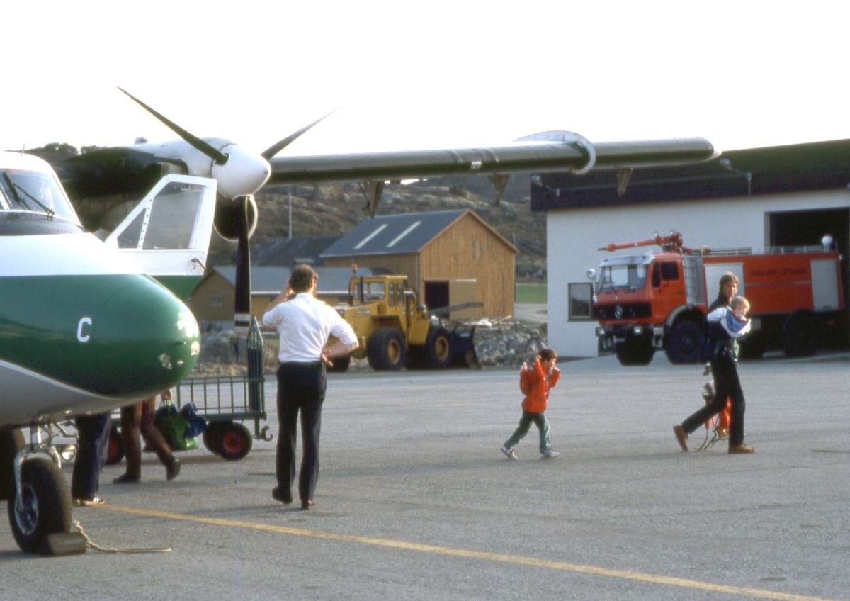Lufthavn (flyplass). Et fly, LN-WFC, DHC-6-300 Twin Otter fra Widerøe parkert. En person (flykaptein/pilot) foran flyet. Flere personer går på land.