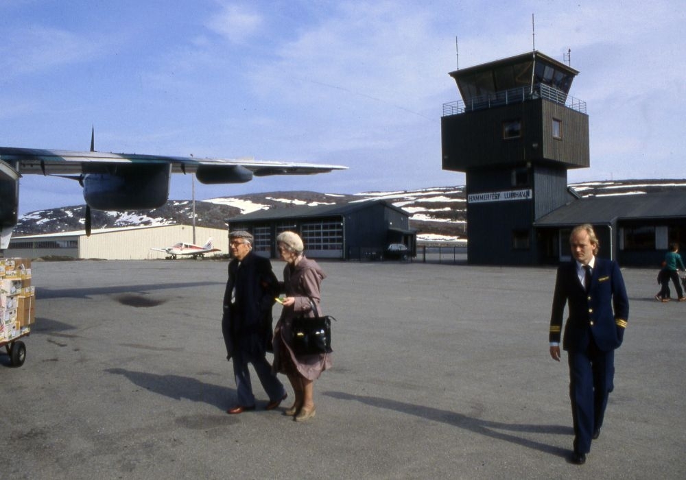 Lufthavn (flyplass). Høyre vinge til et fly, LN-WFL, DHC-7-102 Dash 7 fra Widerøe. To passasjerer og en flyger (pilot) går til flyet.
