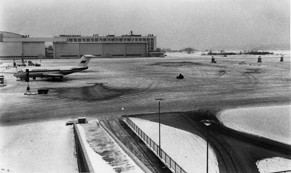 Lufthavn/Flyplass. Fornebu. Et fly, LN-SUN, Fokker F28 Fellowship fra Braathens SAFE, parkert. I bakgrunnen SAS hangar.