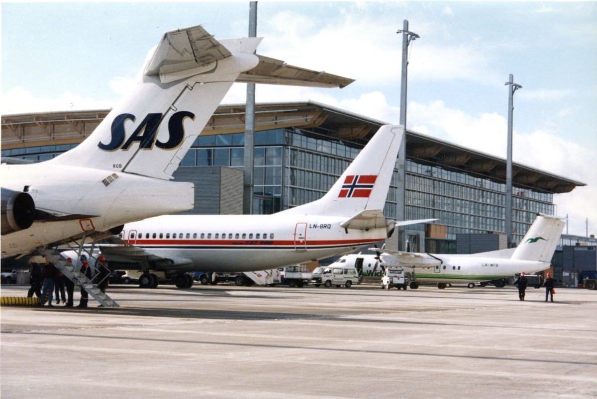 Lufthavn/Flyplass. Gardermoen. På flyoppstillingsplassen (tarmac) foran terminalbygget står tre fly parkert, SAS, Braathens SAFE og Widerøe.
