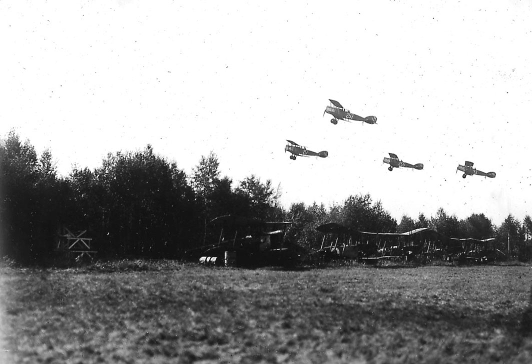 Luftfoto, fire fly i luften, Bristol Fighter nr 251, 257, 255 og 253 tar av. Kamuflerte fly, Avro 504, T1 og Kaje på bakken under. 