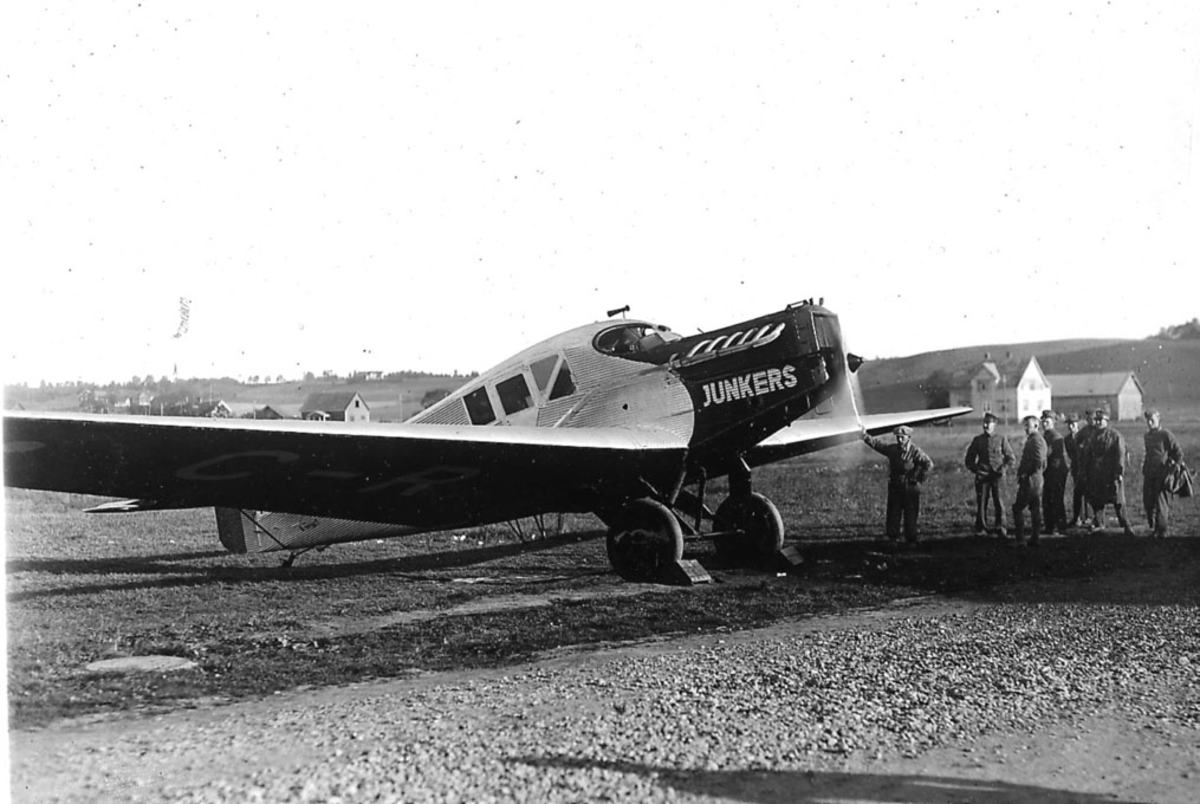 Åpen plass, lufthavn. ett fly på bakken, rumensk Junkers F.13, C-RBIM. Noen personer ved flyet.