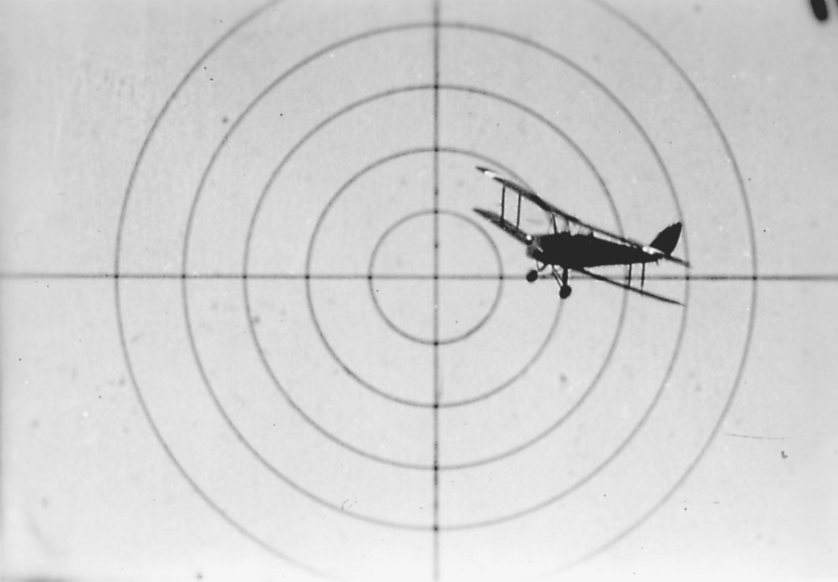 Luftfoto, ett fly i luften, sett gjennom våpensikte.
Tiger Moth i sikte.