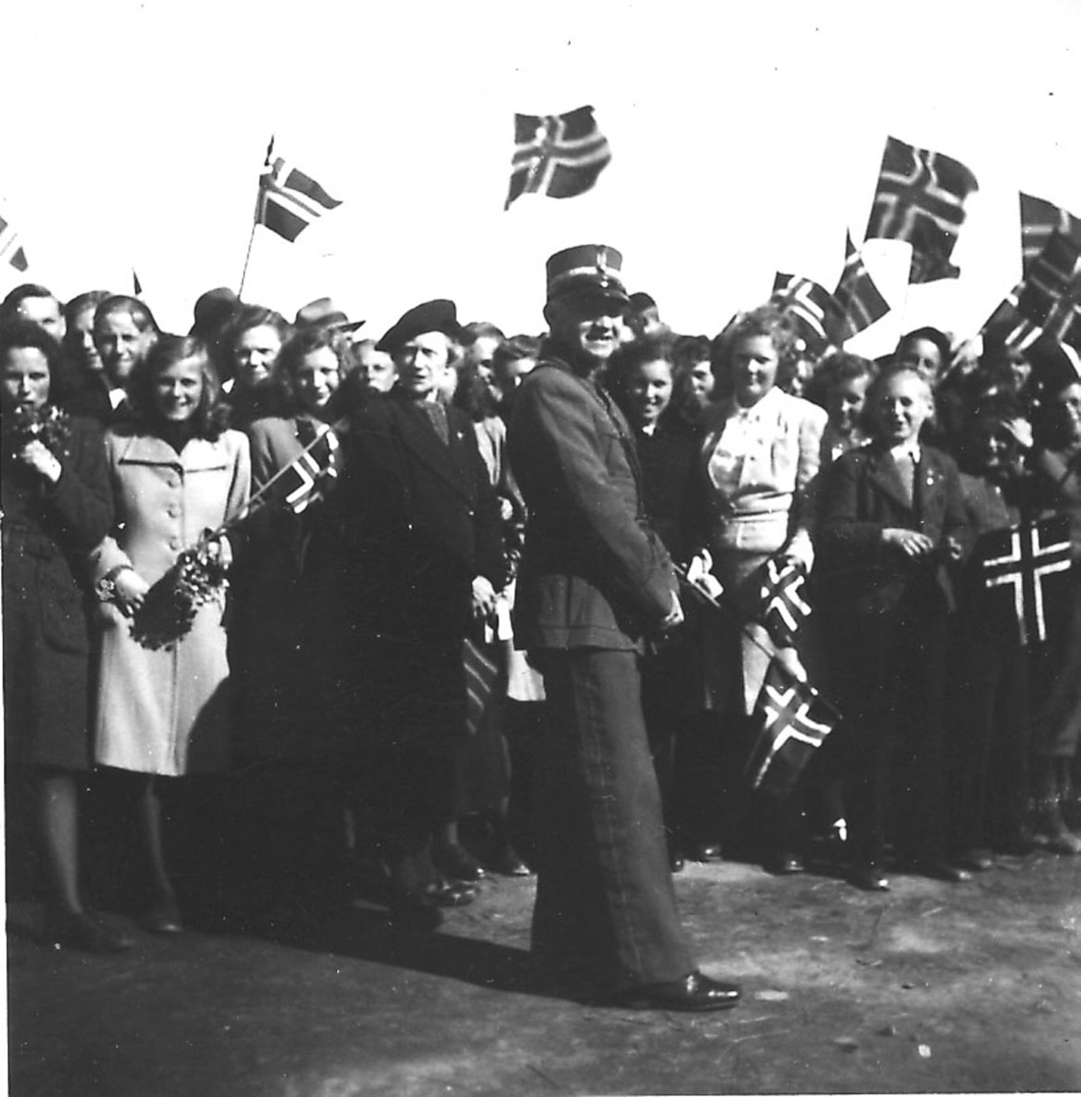 Frigjøringsdagene i Bodø etter krigen  1945. Flere personer, noen med flagg. En person i uniform foran.