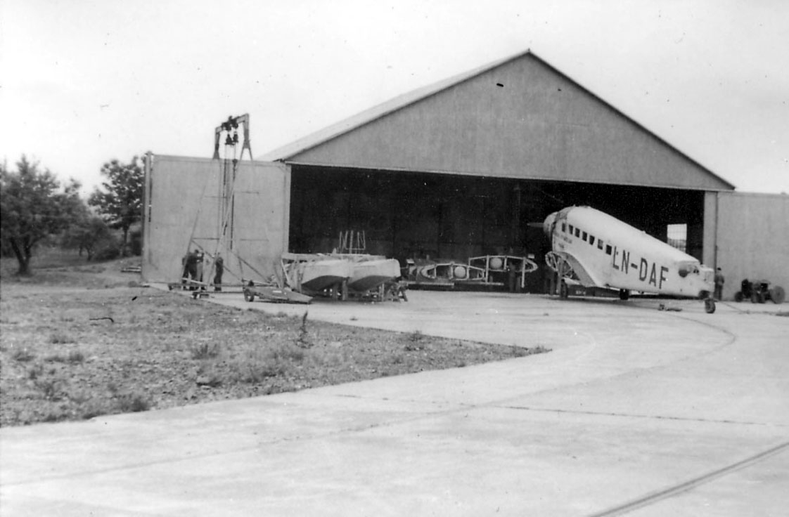 Sjøflyhavn, ett fly på bakken, Junkers Ju 52/3mge LN-DAF, "Najaden", foran en hangarbygning. Vingene og flotørene ligger ved flyet