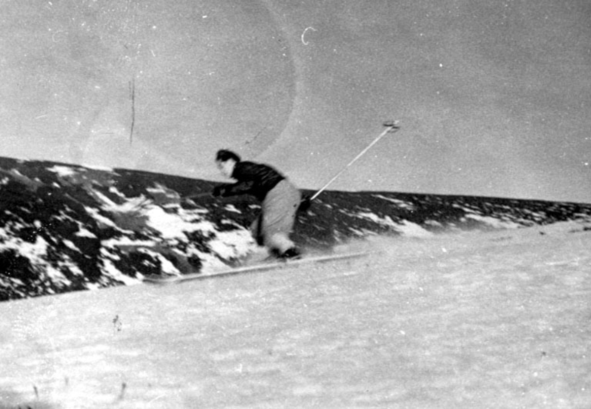 Portrett, en person på ski ned skråning.