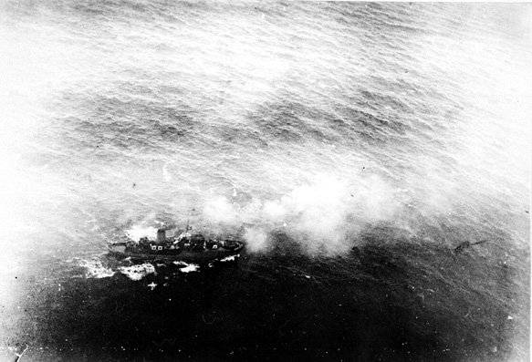 Luftfoto,  fartøy nedenfor, "Arna". Røyk stiger til værs, ant. etter bombetreff. Hav rundt.