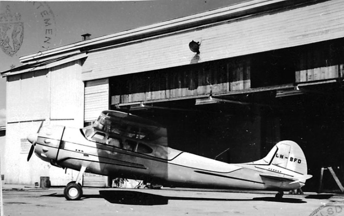 1 fly på bakken, Cessna 195 B, LN-BFD, fra Thor Solberg Aviation A/S. Bygning/hangar bak.