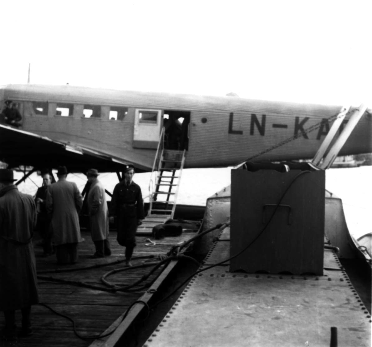 Sjøflyhavn, 1 fly ligger ved kai, Junkers JU-52 3m mg LN-KAF "Askeladden" fra DNL. Flere personer ved flyet.