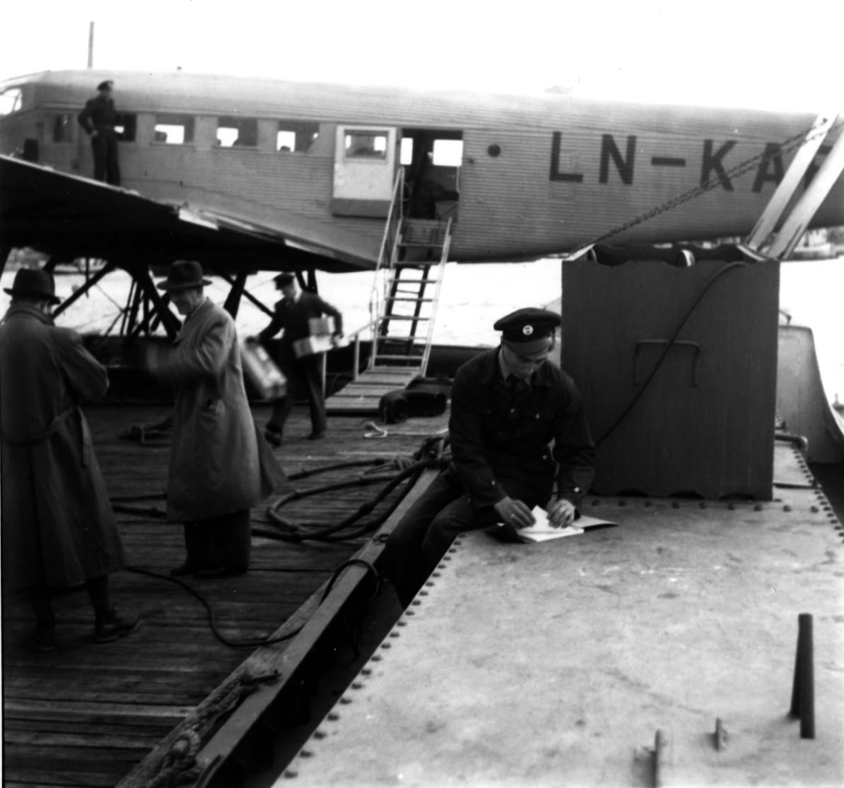 Sjøflyhavn, Ett fly ligger ved kai, Junkers JU-52 3/mg LN-KAF "Askeladden" fra DNL. Flere personer ved flyet.