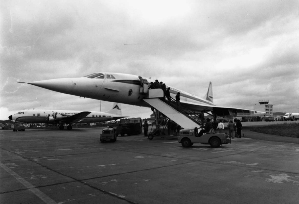 Lufthavn, to fly på bakken. I forgrunnen Concorde F-WTSB fra Air France. Flere kjøretøyer og personer ved flyene.