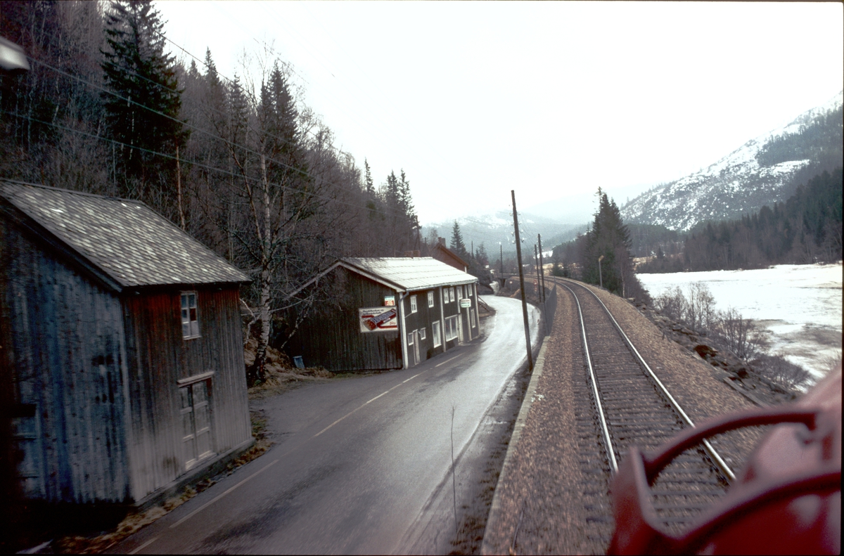Tog 302, dagtoget Trondheim - Oslo, på vei oppover Gauldalen ved Flatberg. Her var det en landhandel som senere ble nedlagt. Riksvei 30 krysset Rørosbanen i en undergang under sporet. Riksvei 30 er lagt om her og går nå i bru over sporet.