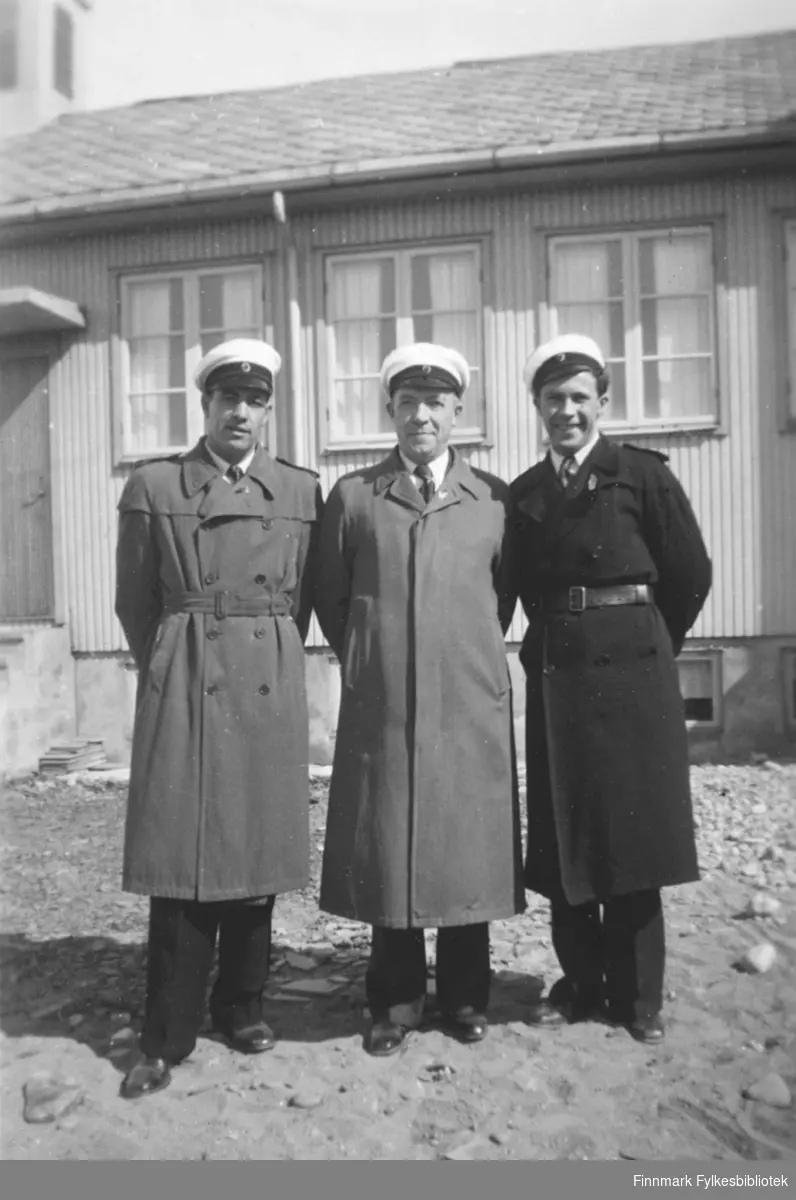 Medlemmer av Vadsø mannssangforening, med sangerluer. Fra venstre Erling og Halfdan Kvam, Oskar Store. Bildet kan være tatt omkring 1960. I bakgrunnen noe som ser ut til å være en gjenreisningskirke, men vi vet ikke hvor bildet er tatt