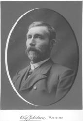 Portrett av ukjent mann. Mannen er kledt i mørk jakke, hvit 