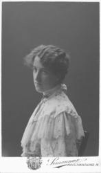 Portrett av ukjent kvinne. Kvinnen sitter på en stol. Hun er