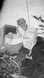 Fotografi av ei kvinne med et barn i ei barnevogn. Kvinnen e