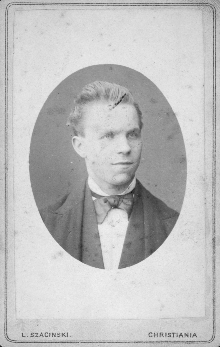 Portrett av en ung mann. Mannen har på seg dress og sløyfe rundt halsen. Det er ukjent hvem han er. Bildet kan være tatt på 1860-tallet, men dette er noe usikkert. Det er likevel tatt mellom 1850-1894.