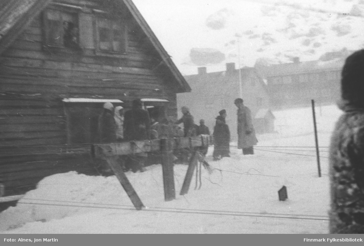 Skirenn i Øksfjord, 1954. Folk søker ly bak 'Hans Hansen-gården'. Helt bakerst i bildet prestegården