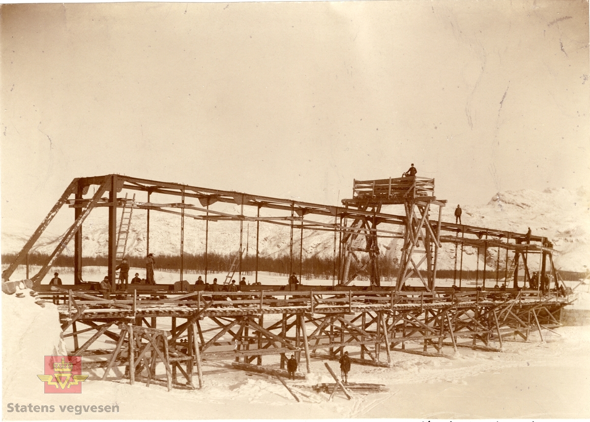 Nordreisa Bro under oppbygging år 1899. Stillas bygd på isen for å dra på plass stålkonstruksjonen.