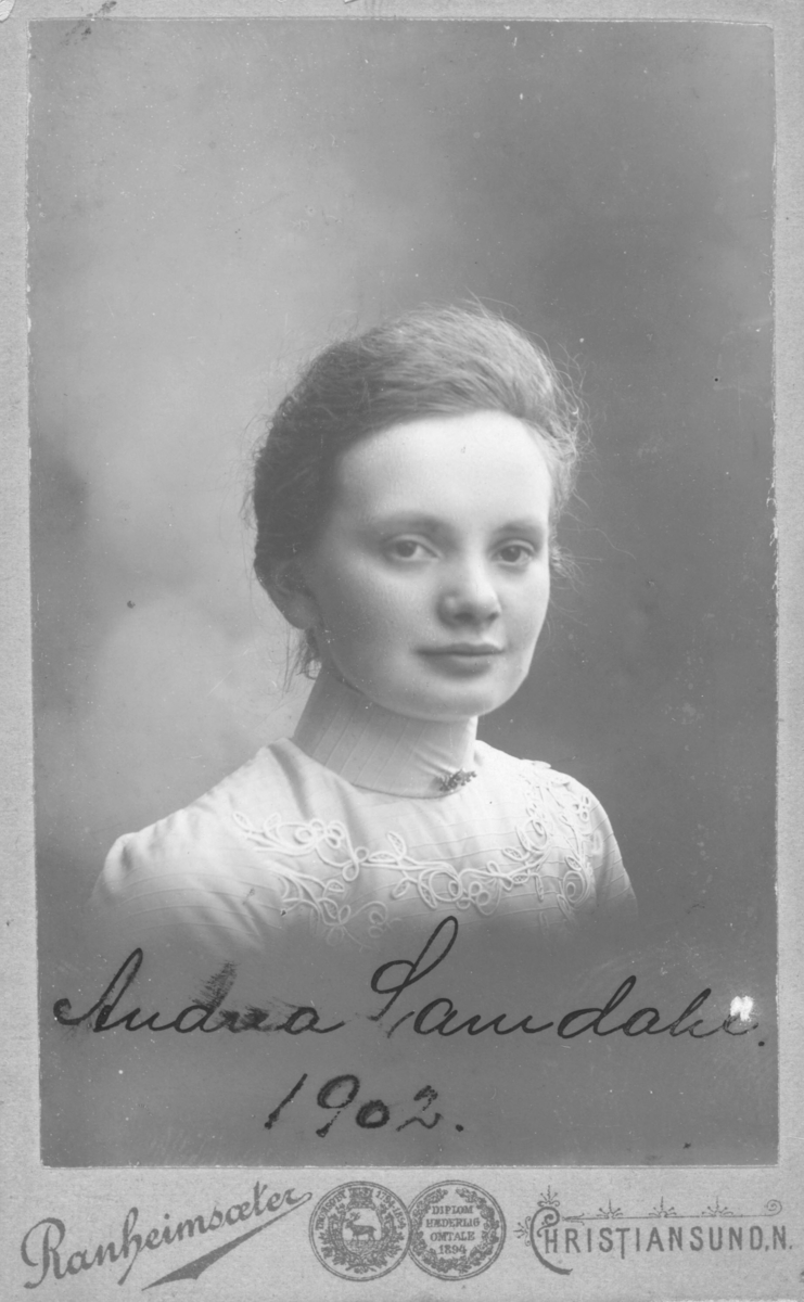 Portrett av en ung kvinne, på bildet står det skrevet "Andrea Samdahl, 1902". Andrea er iflg. Digitalarkivet født i Kristiansund kjøpstad og har som yrke "Husgjerning".