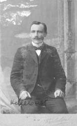 Portrett av mann i halvfigur, sittende. På bildet er det not