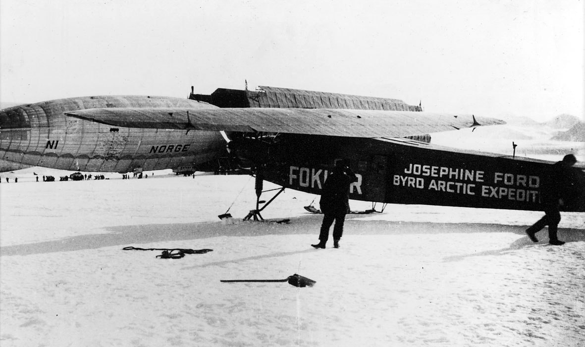 1 fly på bakken, Fokker, med påskrift "Josephine Ford Byrd Arctic Ekspedition". Luftskipet Norge bak. Mange personer i området. Snø på bakken.