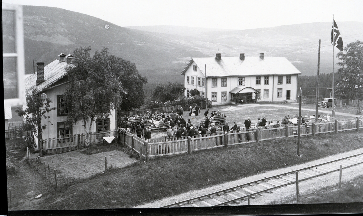 Mennesker samlet utenfor middelskolen og realskolen i Aurdal, med middelskolens gymnastikksal i bygningen til venstre.