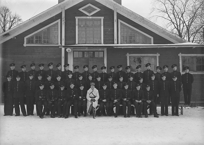 Vapensmedskolans elever och lärare vid F 3 Östgöta flygflottilj, 1940. Grupporträtt framför byggnad, vintertid.