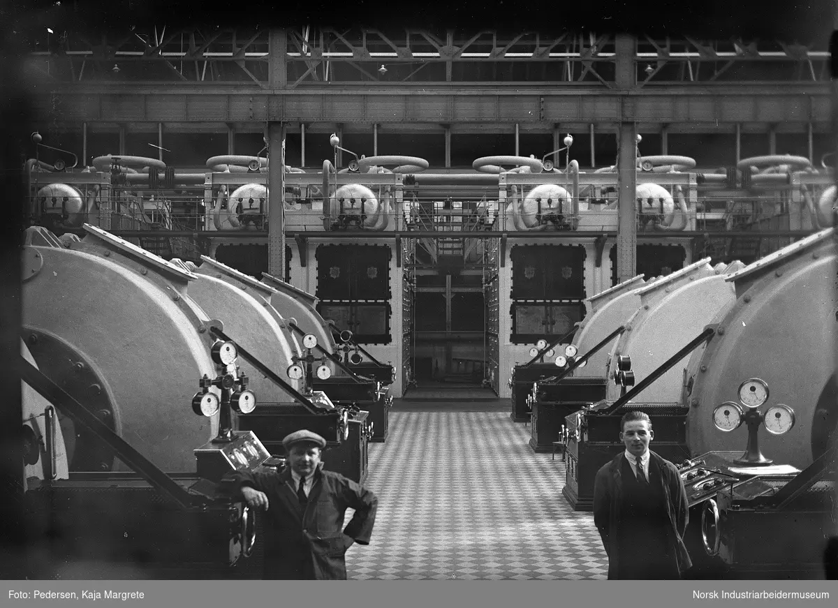 Ovnshus med to arbeidere stående foran maskinene.