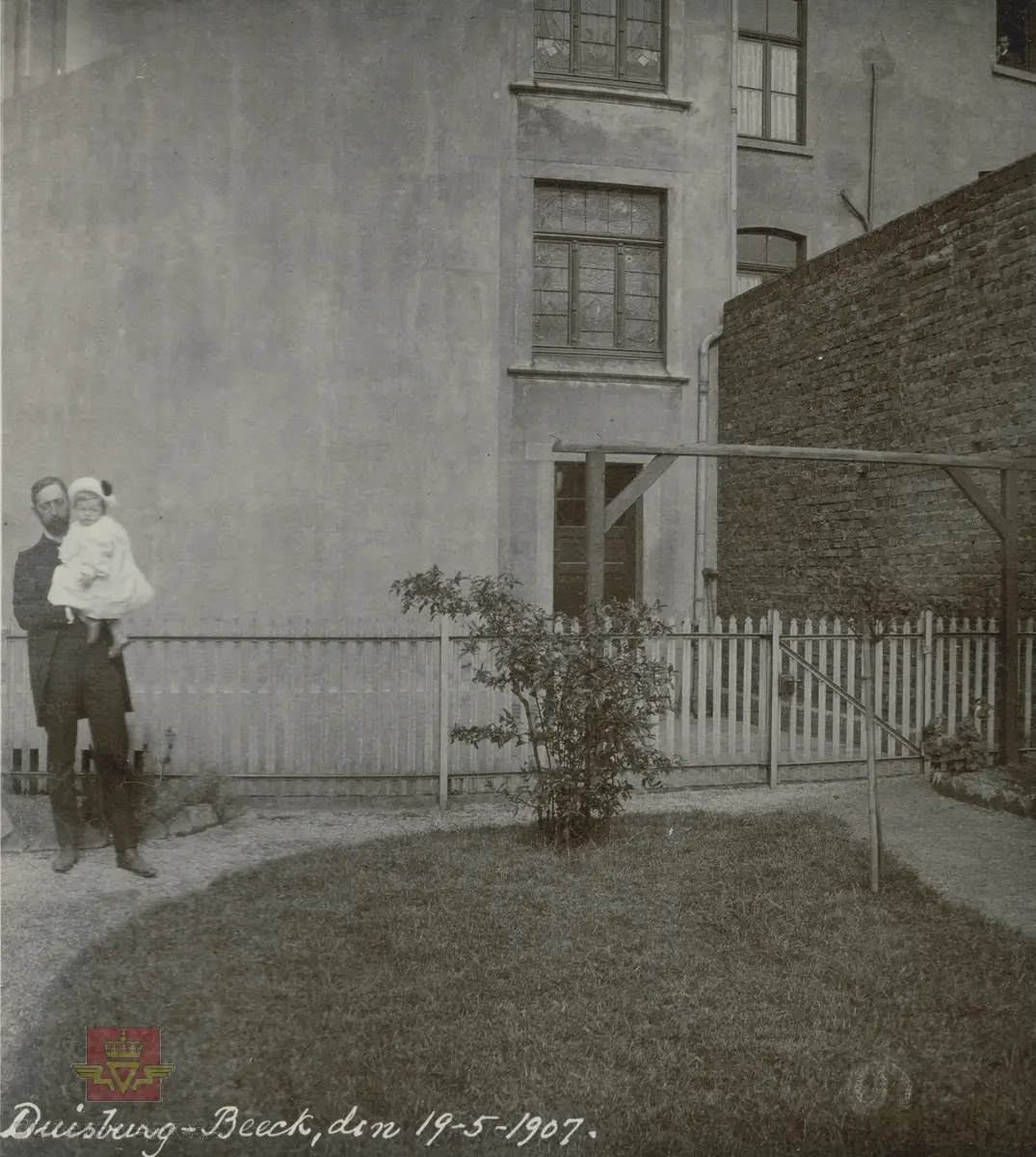 Album fra 1903-1908.  Dresskledd mann med et barn på armen. Duisburg-Beeck, 19.05. 1907.