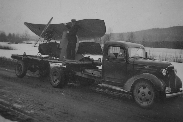 Transport av flygplan Flygande Loppan på en lastbil. En man står på lastbilsflaket. Vintertid.