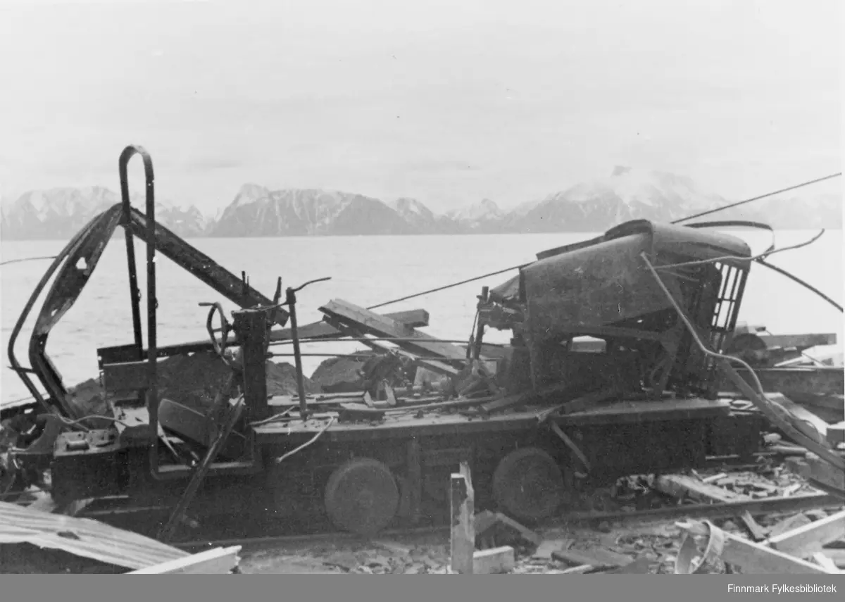 Ødelagt maskineri, muligens etter krigen. I bakgrunnen ser man fjell og fjord.