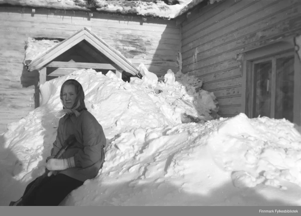 Herlaug Mikkola sitter i snøen utenfor hovedhuset på gården Mikkelsnes, ca. 1952. Dette må ha vært en skikkelig snøvinter!