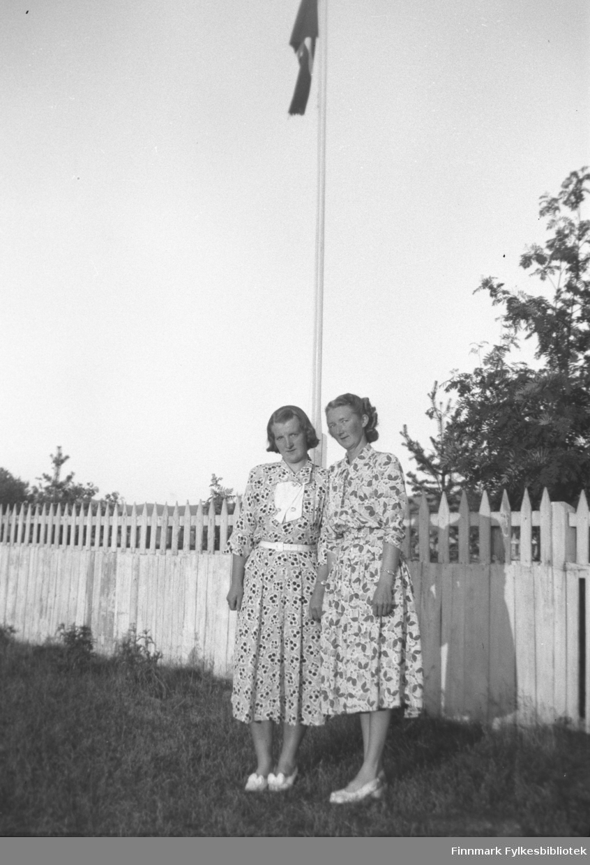 Søstrene Astrid og Marine Mikkola foran flaggstanga på gården Mikkelsnes