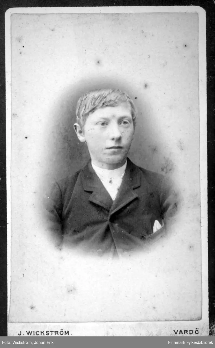 Portrett av en ung mann, med fornavn Axel, iført mørk dressjakke med hvit skjorte under. I brystlomma har han et lyst lommetørkle.