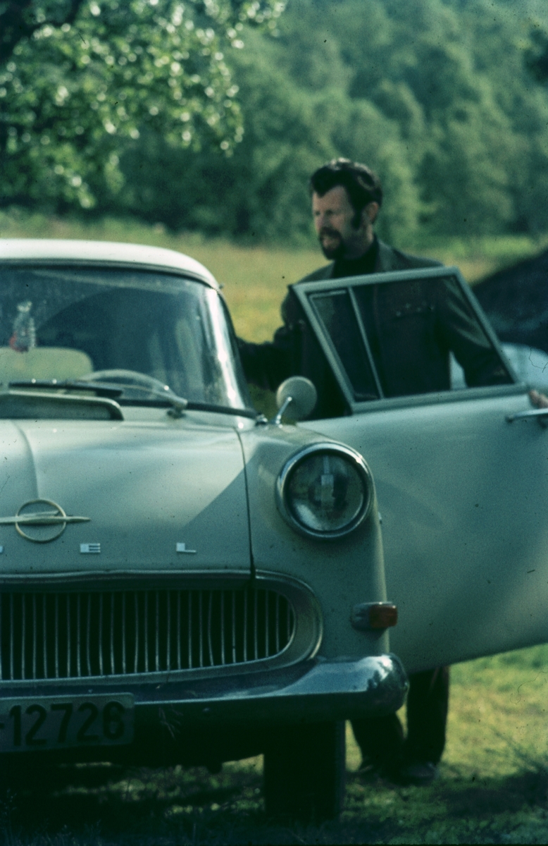 Sevald Eilertsen står på førersiden av en Opel, med døra åpen.