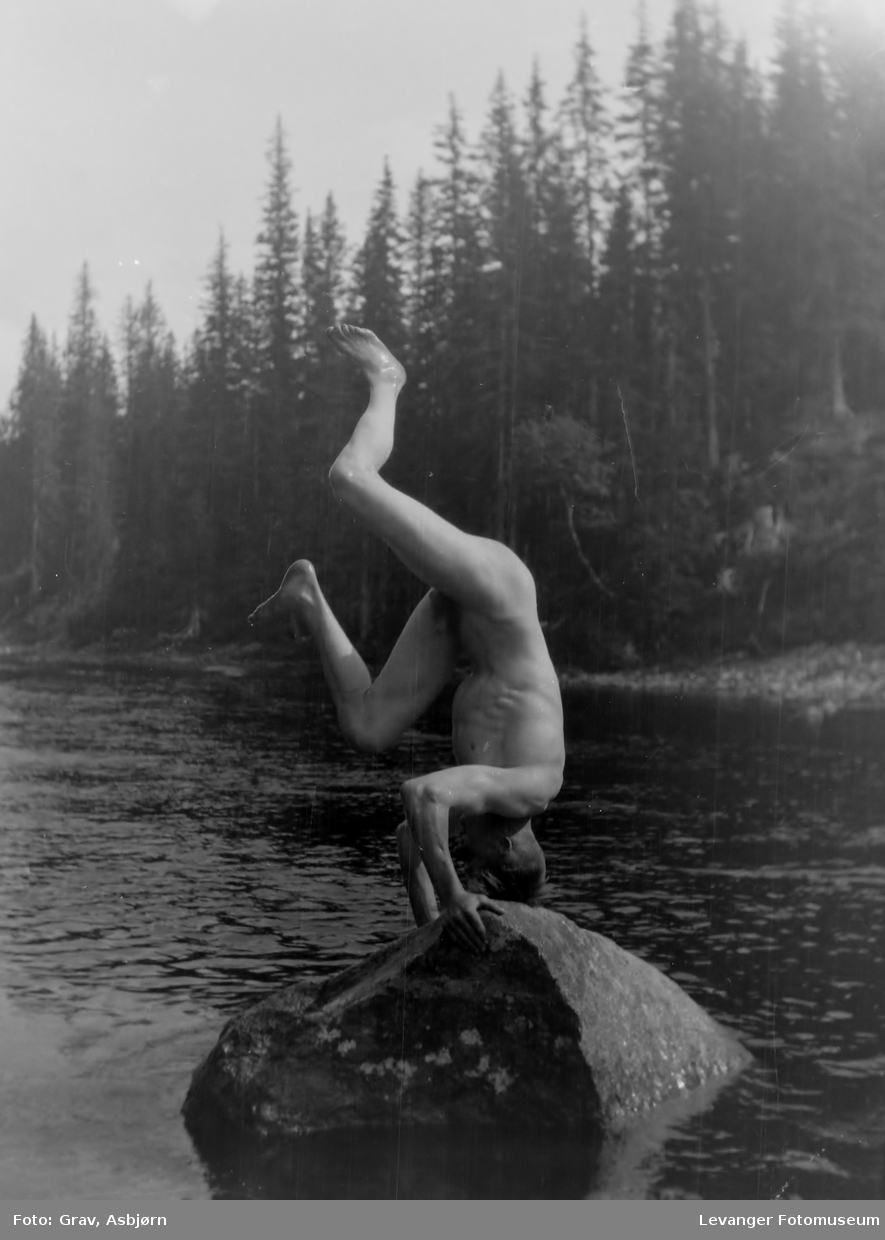 Mann står på hodet på en stein i elva