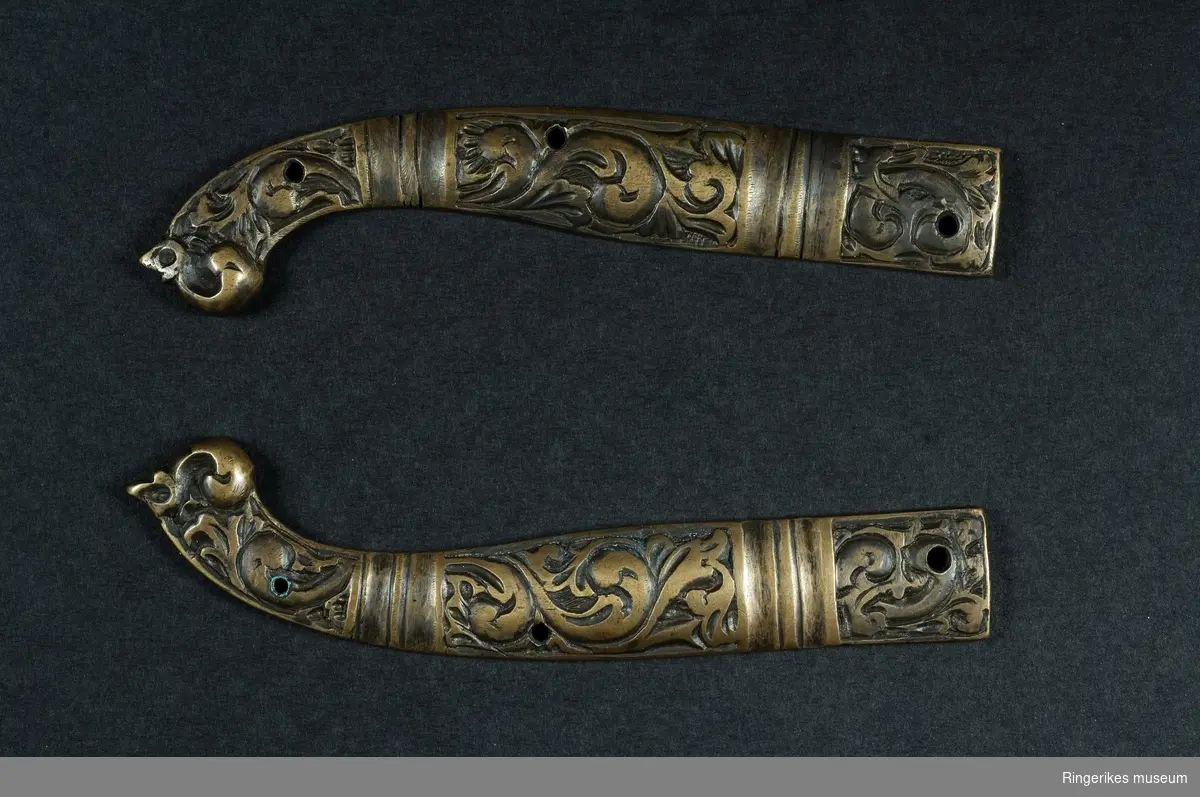 Knivskaft/knivskaftbeslag i dragehodestil.
Laget av bronse